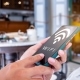 Public WiFi woman hand using smartphone with wifi icon in cafe shop background
