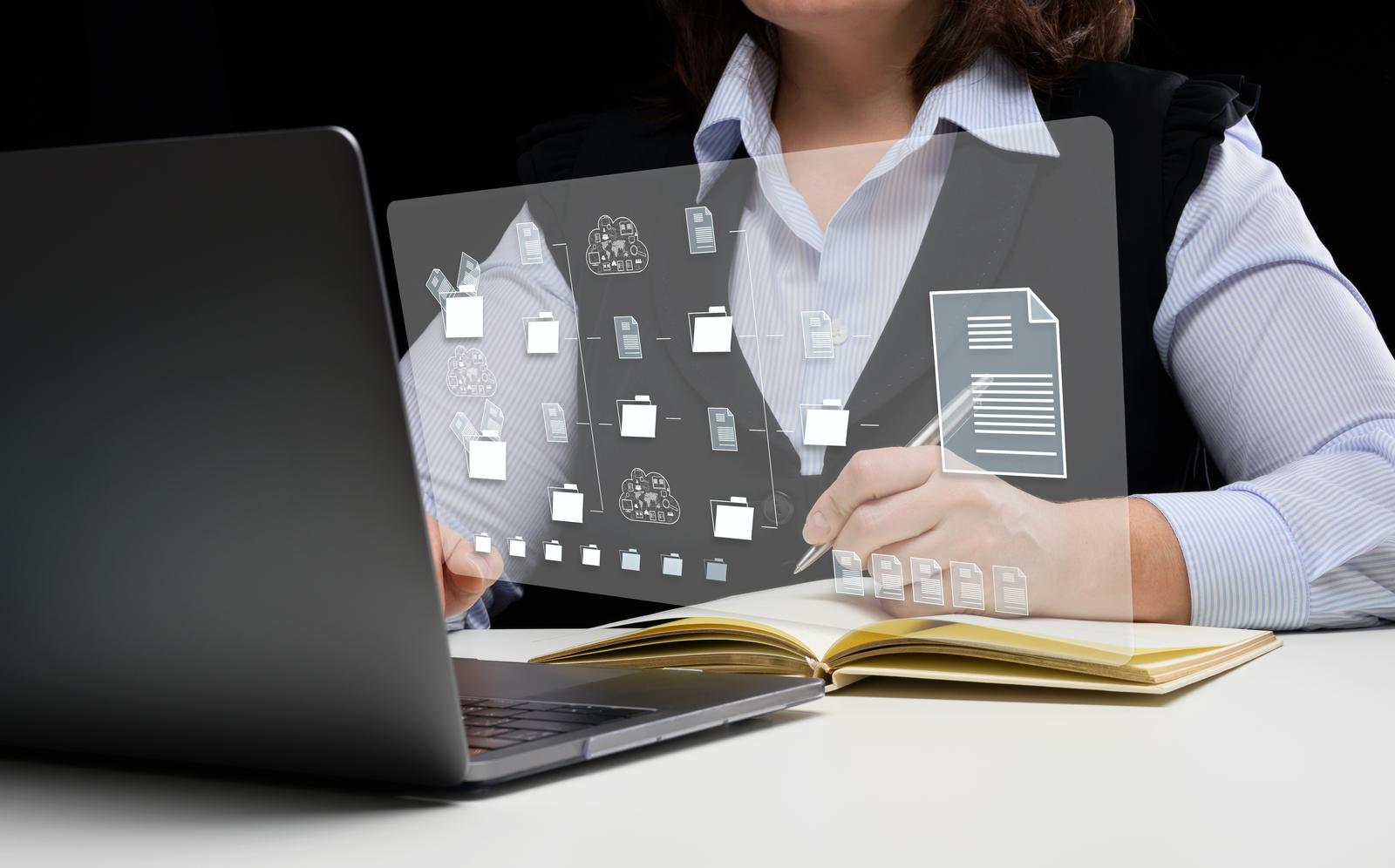 woman sits at a table and works with a laptop document management mystem dms software for automating archiving and efficient management